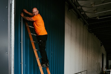 Man op layher houten ladder
